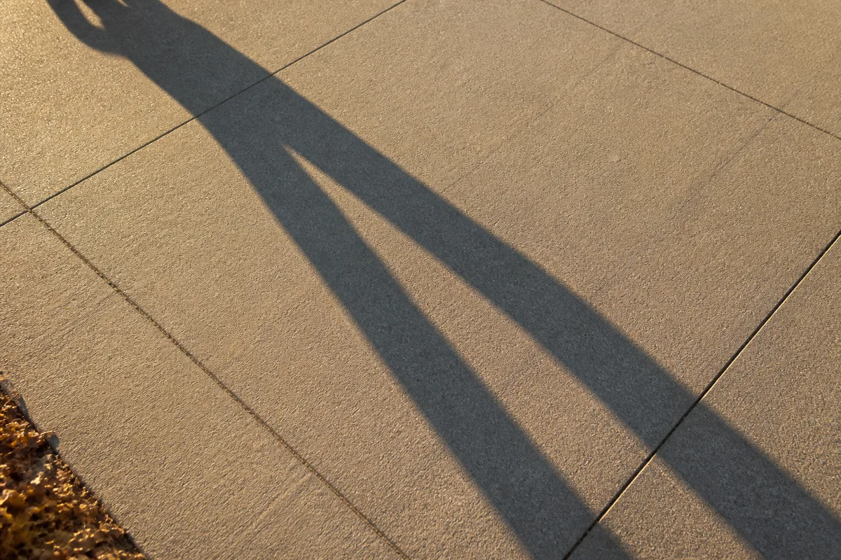 Ombre portée d&rsquo;un marcheur sur un trottoir en fin d&rsquo;après-midi